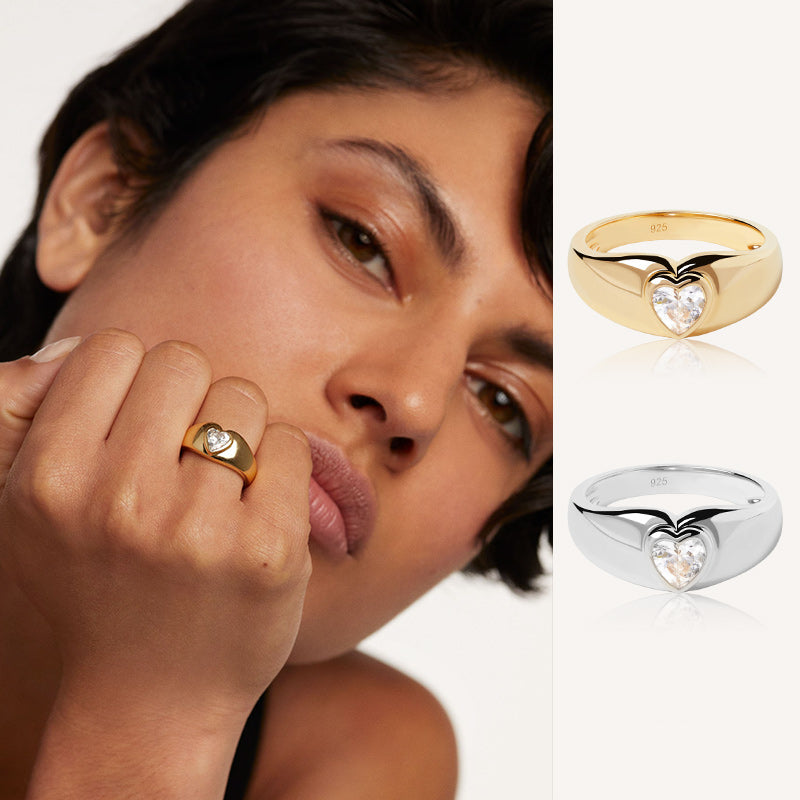 A young woman models a gold ring with a heart-shaped gem; the same ring is shown in gold and silver on the side."