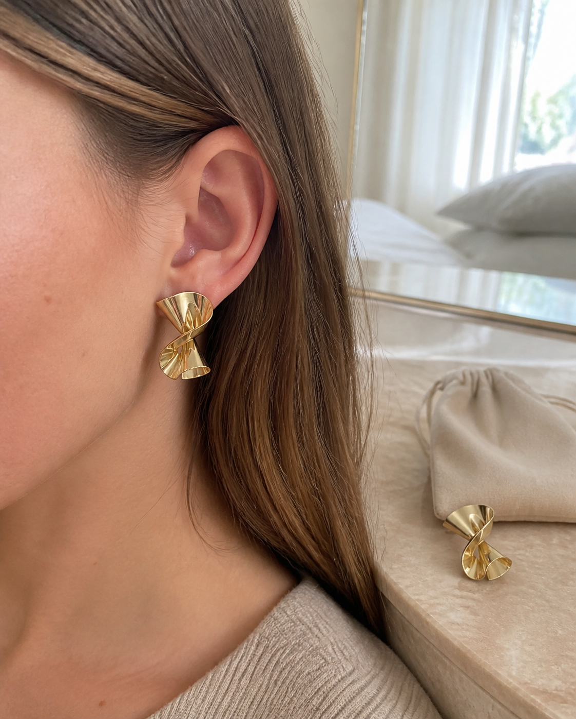 Gold twisted stud worn in a soft neutral setting